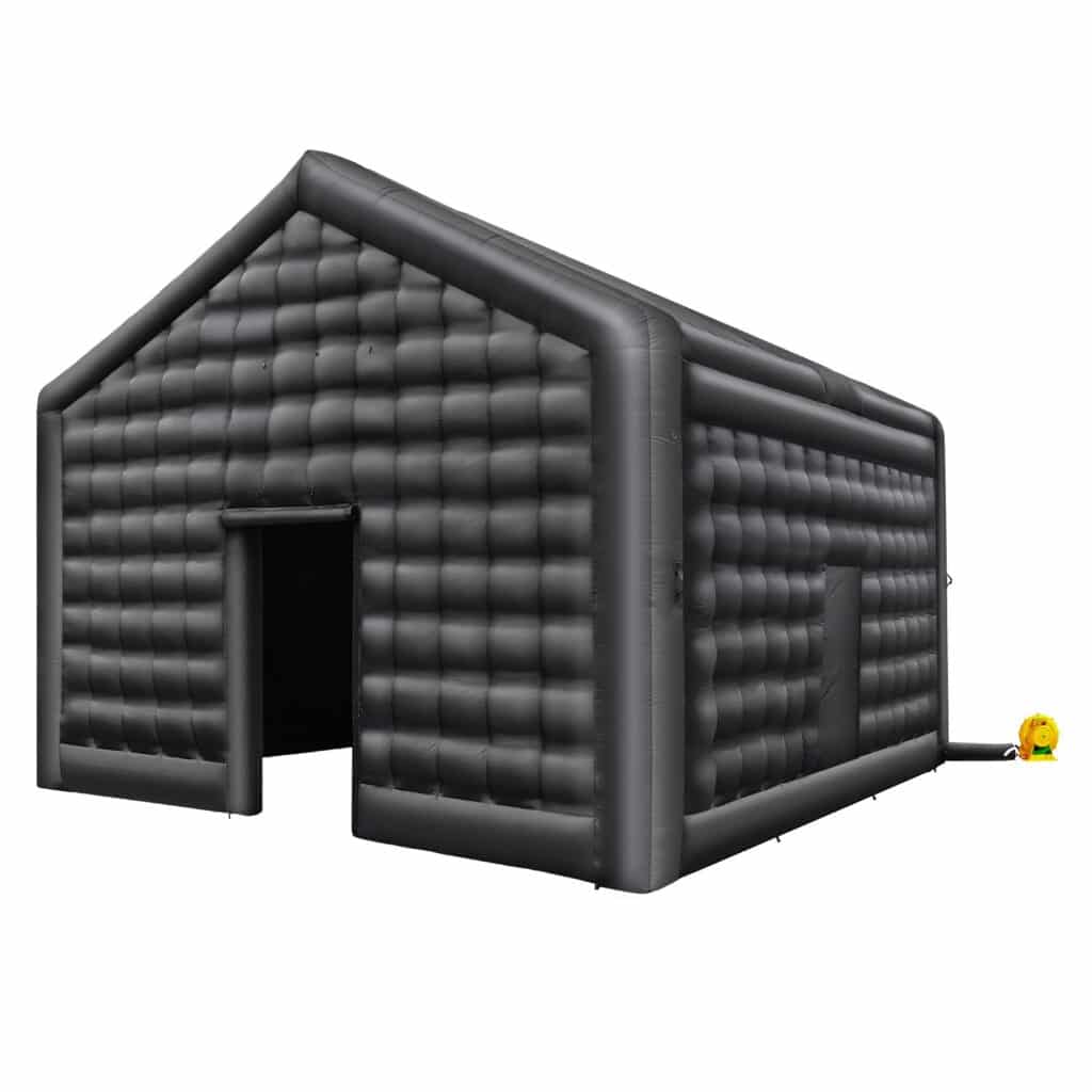 Eine große, schwarze aufblasbare Struktur in Form eines Hauses mit Spitzdach. Sie hat offene Eingänge an Vorder- und Seitenwänden. Ein gelbes Gebläse sorgt für die Luftzirkulation. Die Oberfläche wirkt gesteppt.